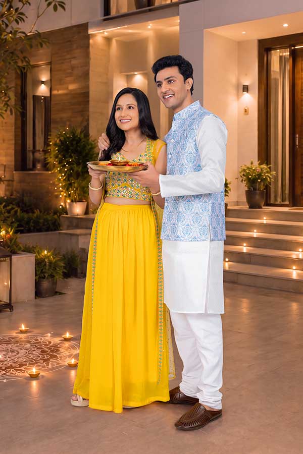 Indian couple celebrating Diwali together with traditional puja thali at home entrance