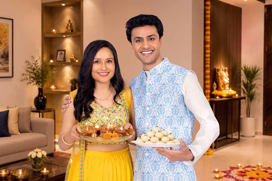 Young Indian couple celebrating Diwali with diya thali and traditional sweets