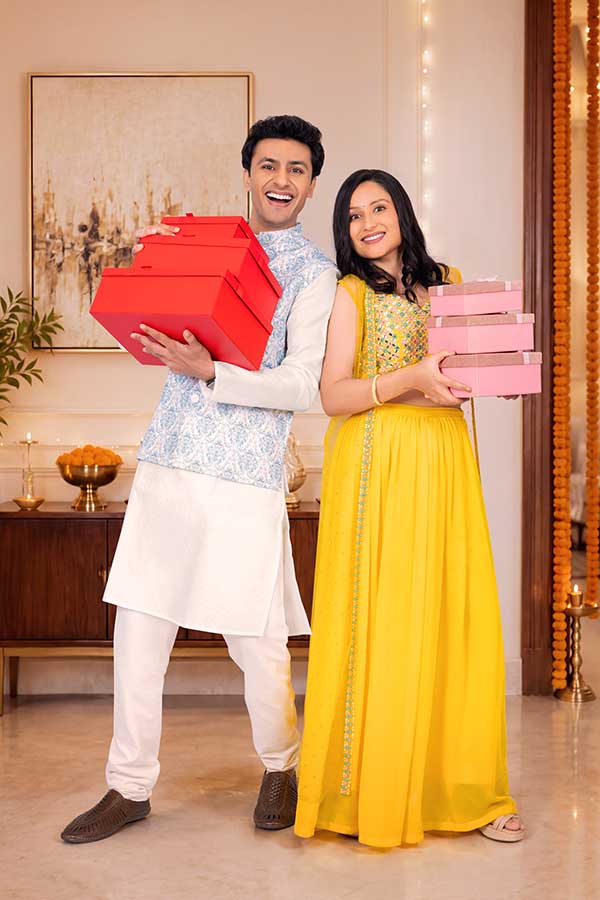 Happy Indian couple holding festive gift boxes during Diwali celebration