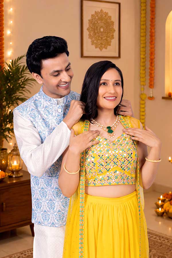 Indian husband helping wife wear elegant necklace for festive celebration