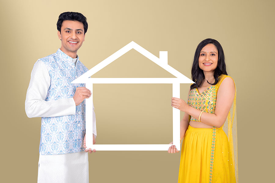 Indian couple holding house frame symbol for dream home concept