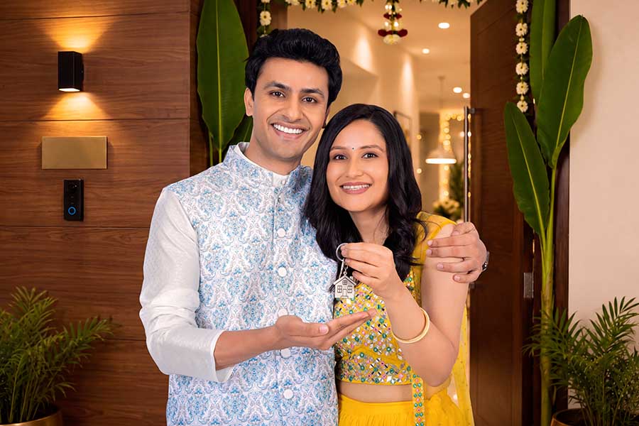 Happy Indian couple presenting house key after buying new home
