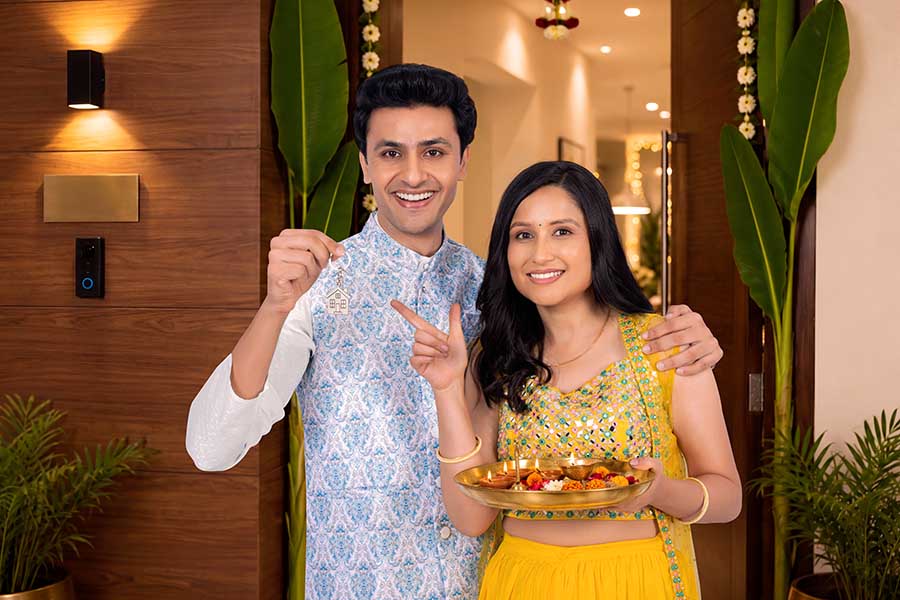 Indian couple celebrating new home with house key and housewarming welcome ritual