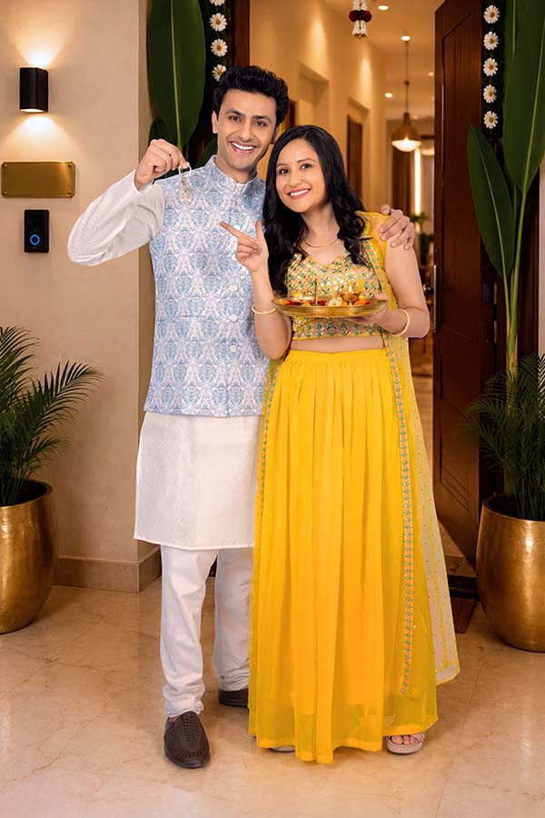 Indian couple welcoming new home with house key and festive puja thali