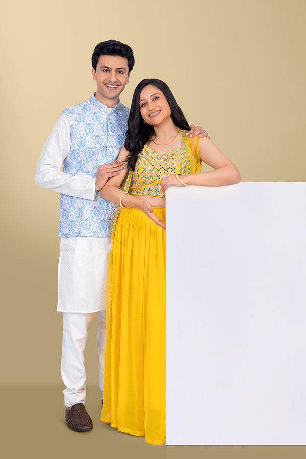 Indian couple standing beside blank white advertising board