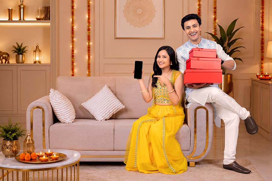 Indian couple promoting festive online shopping with smartphone and gift boxes