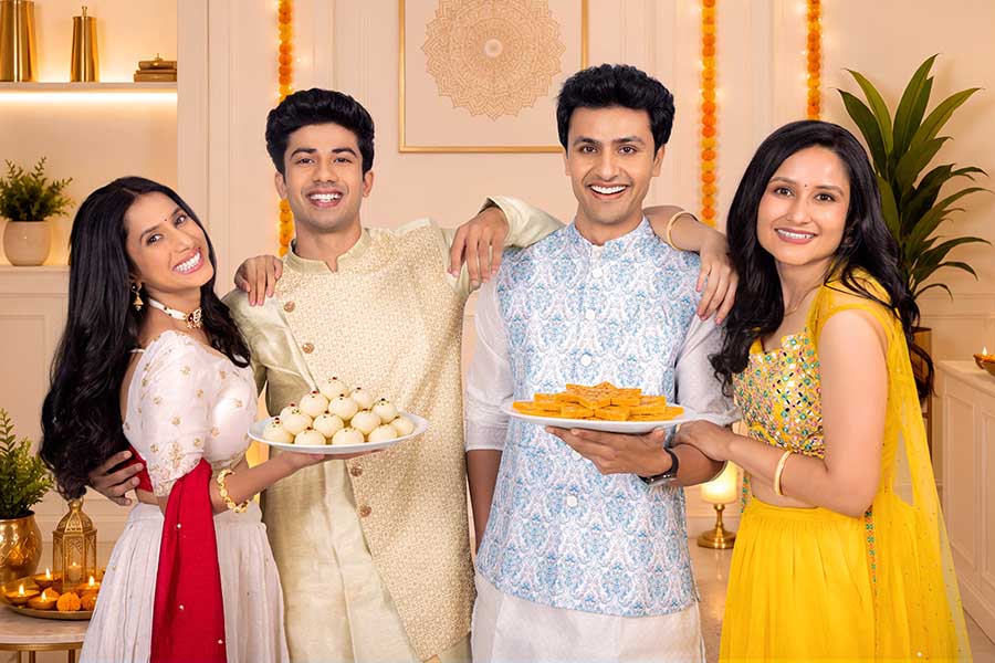Indian friends holding traditional Diwali sweets and festive desserts
