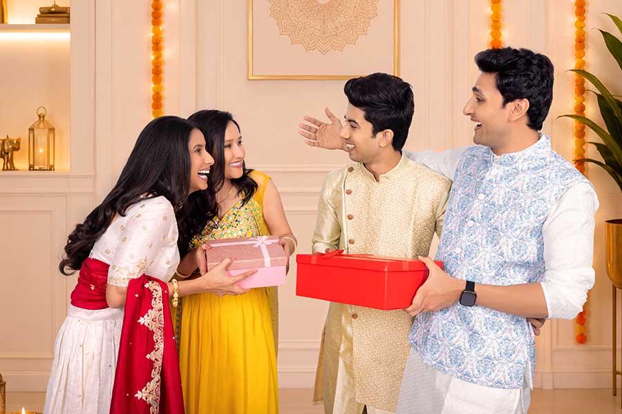 Indian friends exchanging Diwali gift boxes at festive home celebration