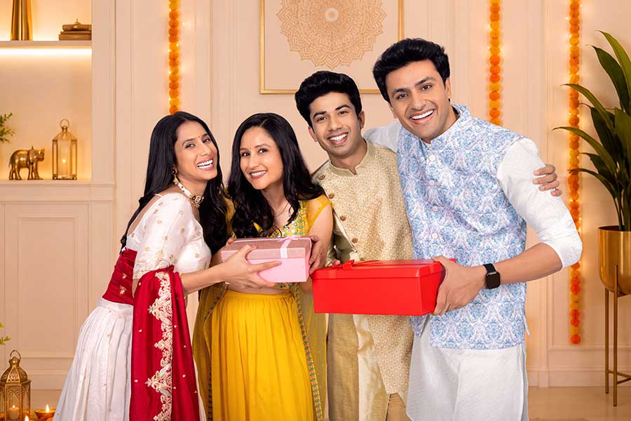 Happy Indian friends posing with festive gift boxes during Diwali