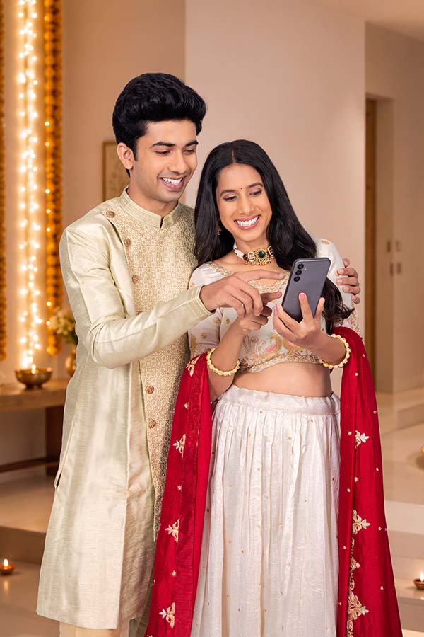 Indian couple using smartphone during festive celebration at home