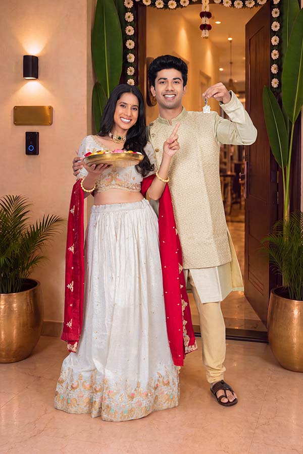 Indian couple celebrating festival with new home keys at decorated entrance