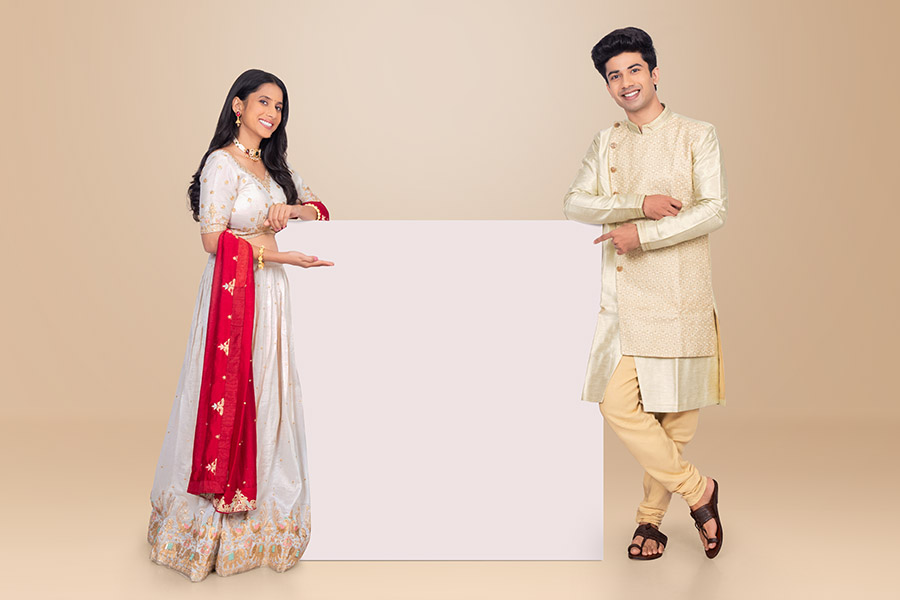 Indian festive couple presenting blank advertising board with copy space