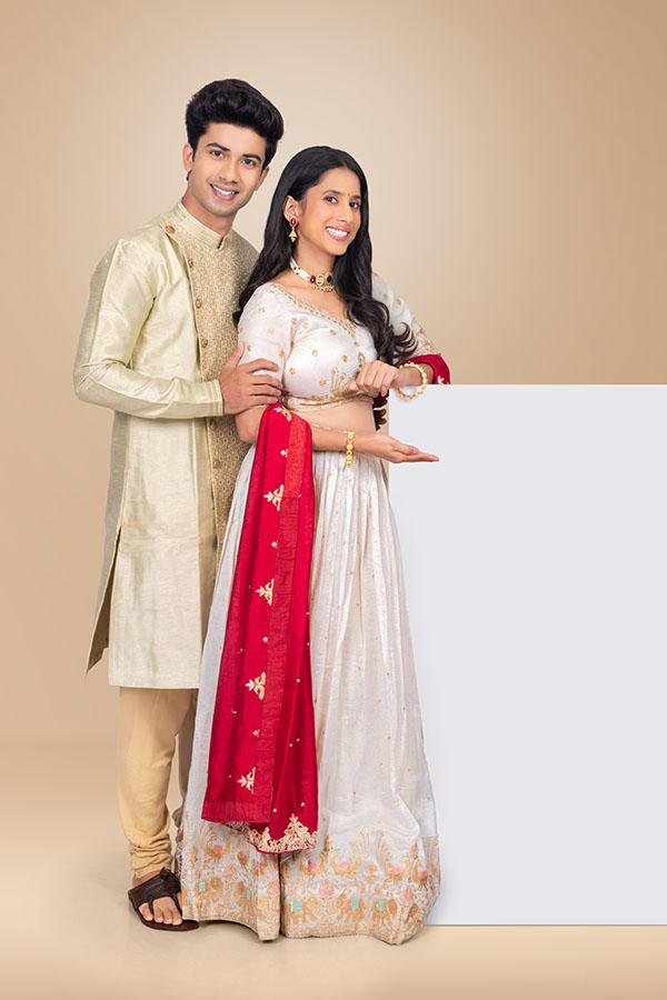 Indian festive couple presenting blank advertising board in traditional attire