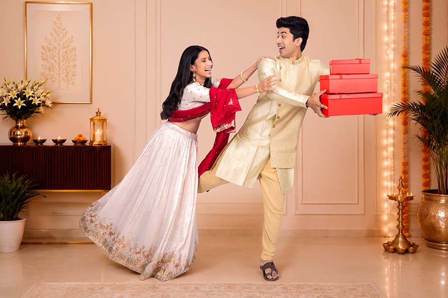 Playful Indian couple celebrating Diwali with festive gift boxes