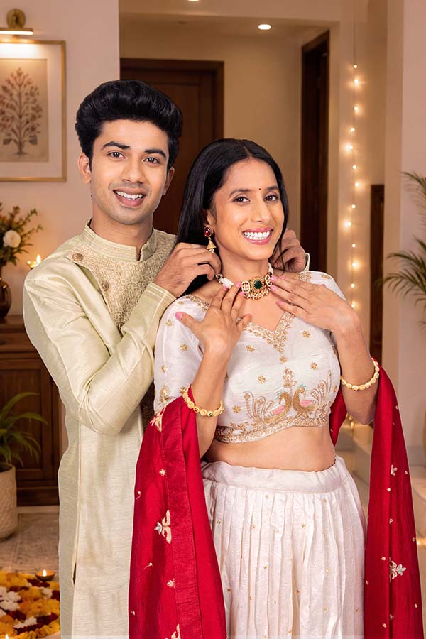 Indian husband helping wife wear festive necklace during Diwali