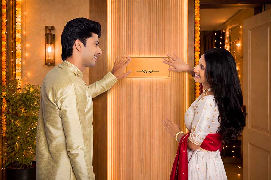 Young Indian couple admiring their new home nameplate