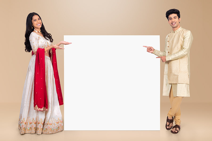 Indian festive couple presenting blank display board for promotions