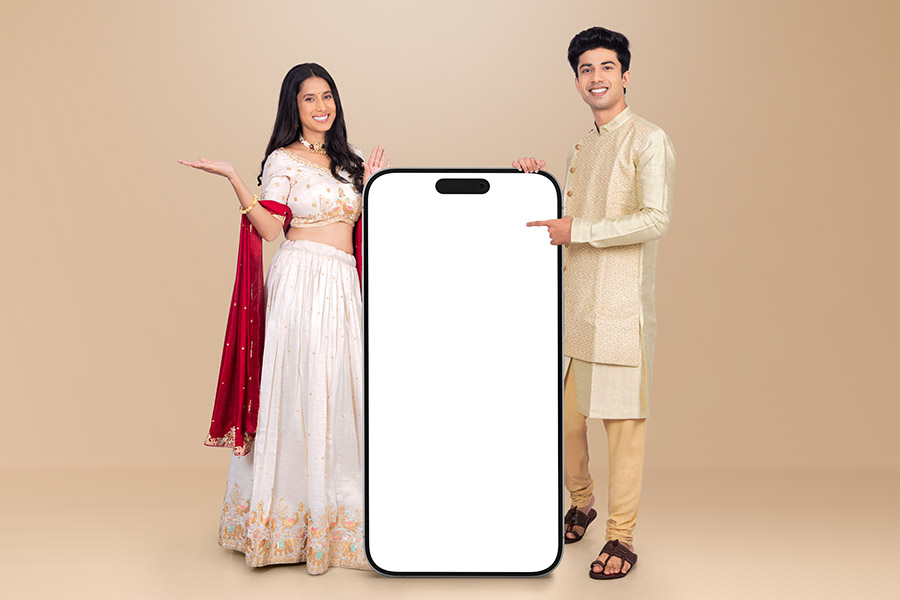 Indian festive couple presenting oversized smartphone mockup