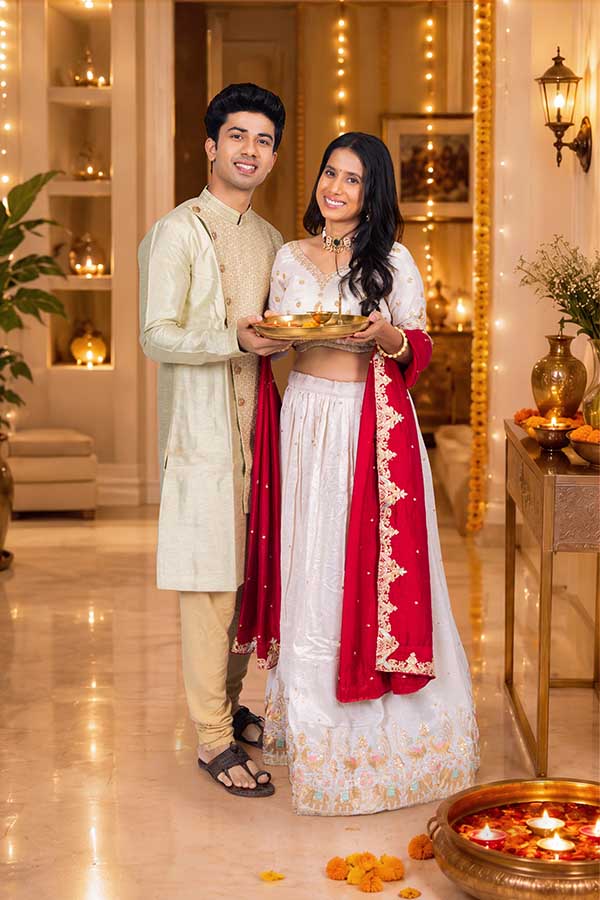 Indian couple holding festive puja thali during Diwali celebration indoors