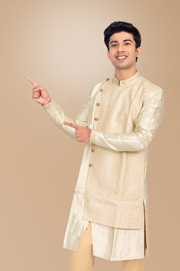 Young Indian man pointing at copy space in elegant festive sherwani