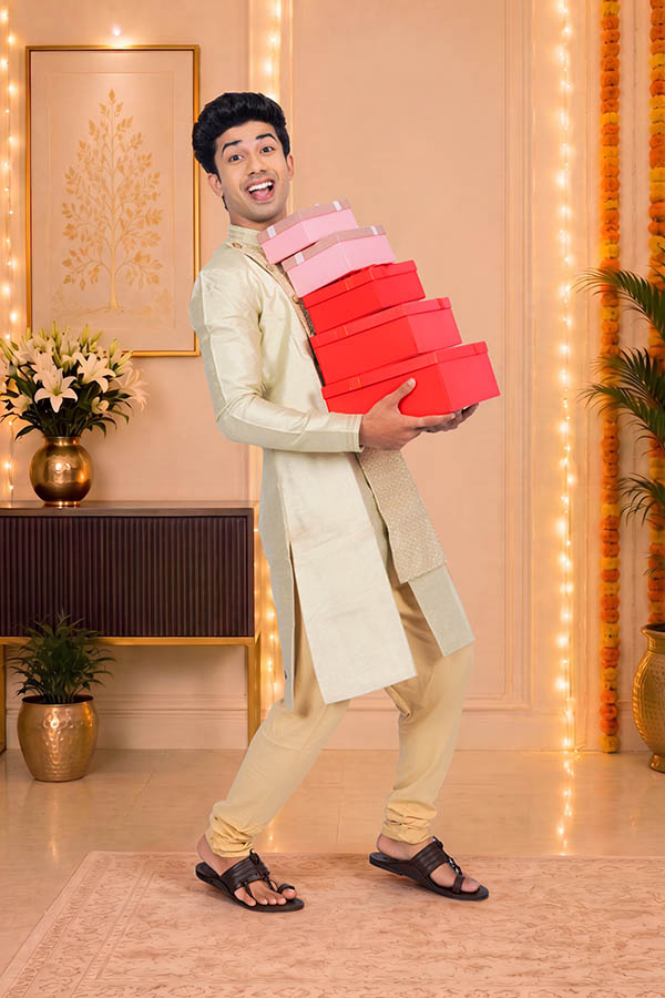 Cheerful Indian man balancing festive gift boxes during celebration