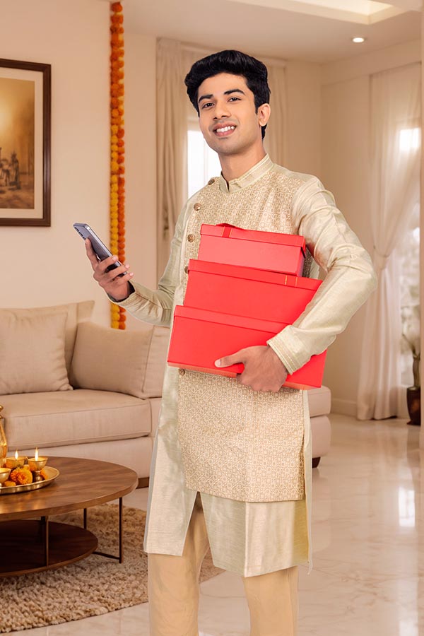 Young Indian man carrying festive gifts while checking smartphone