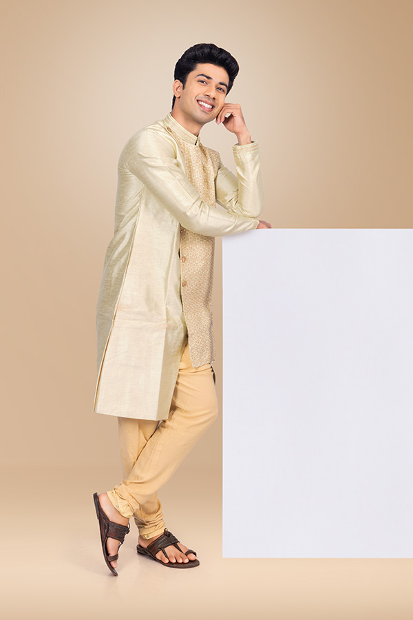 Thoughtful Indian man posing beside blank promotional board in sherwani