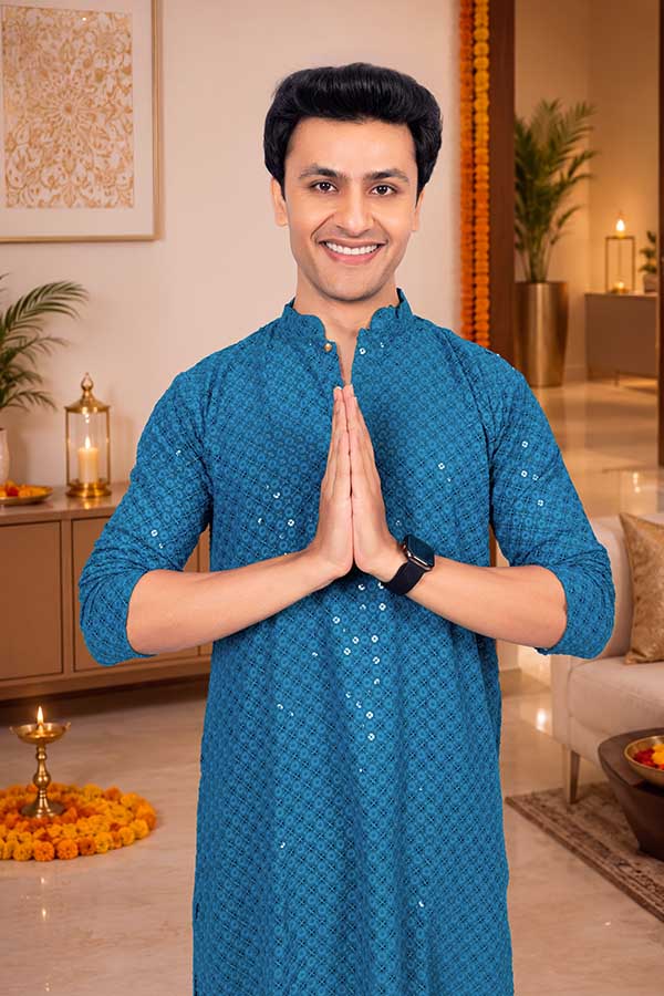 Young Indian man greeting with namaste in festive ethnic wear