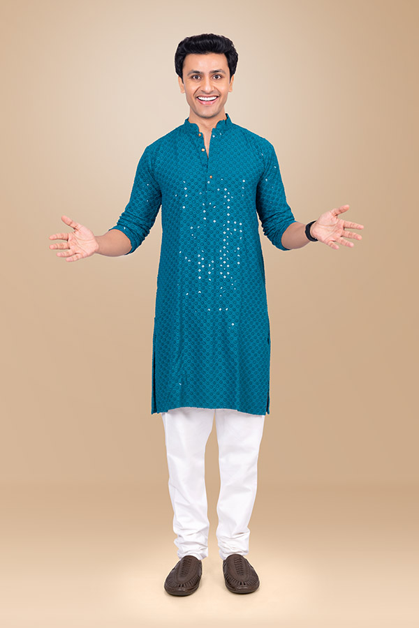 Smiling Indian man in blue kurta welcoming guests during festive celebration