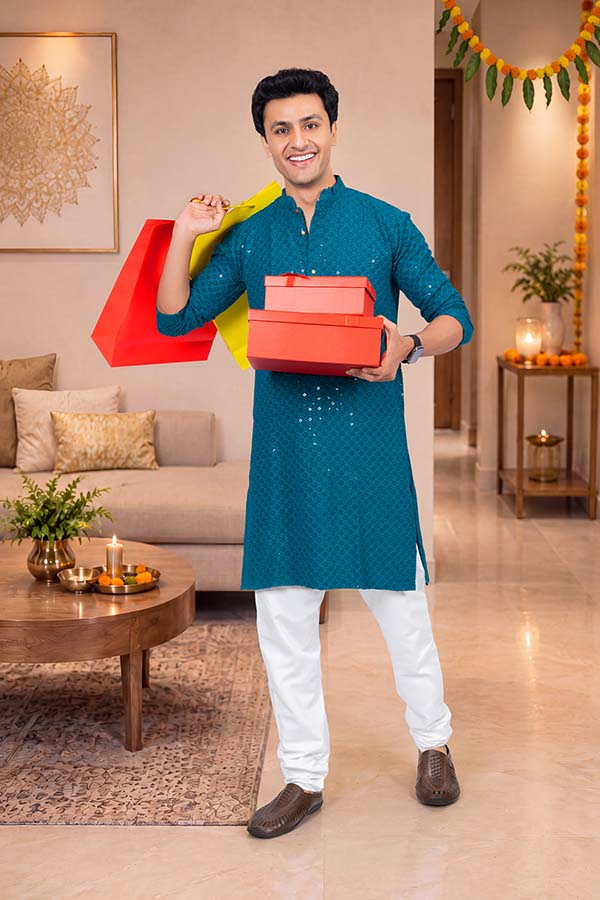 Happy Indian man holding shopping bags and festive gift boxes