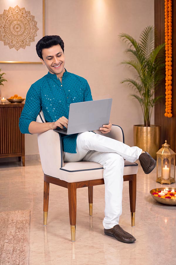 Young Indian man working on laptop during festive celebration at home