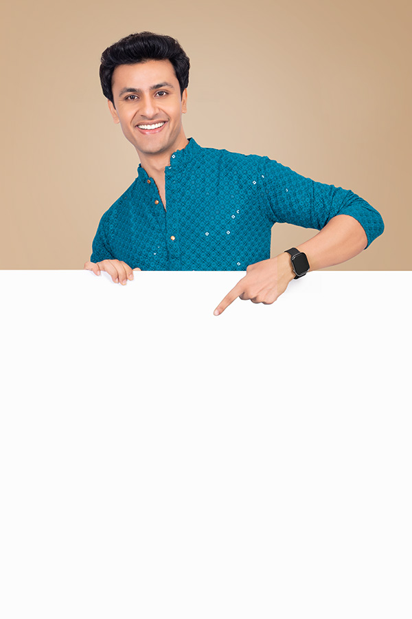 Smiling Indian man pointing downward at blank banner in festive attire