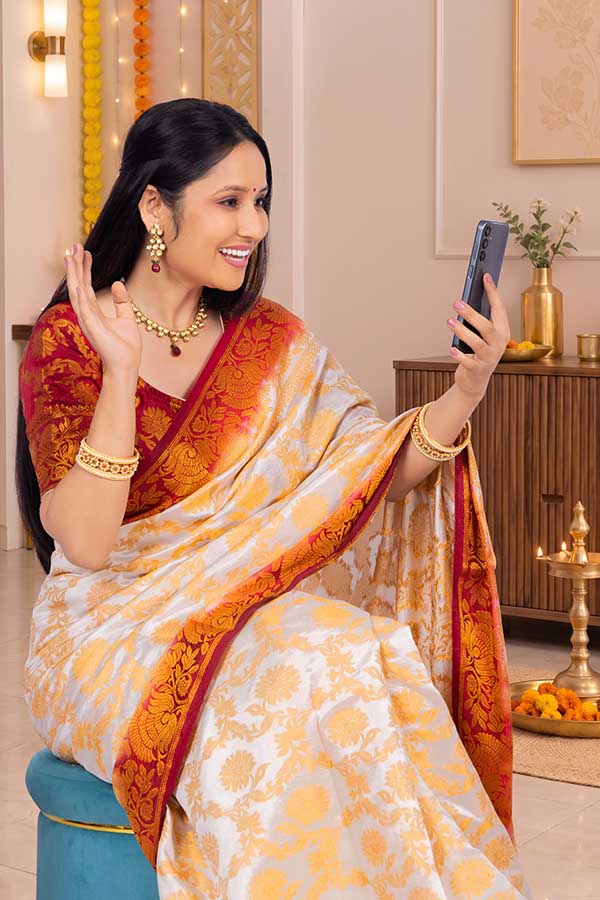 Indian woman enjoying festive video call in traditional saree at home