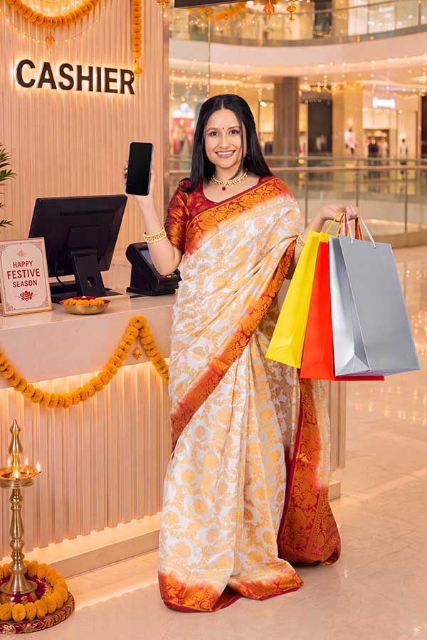 Indian woman displaying smartphone and shopping bags during festive retail season