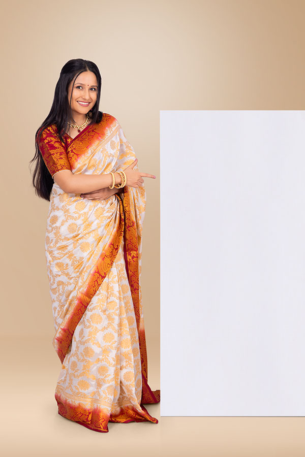 Smiling Indian woman pointing at blank display board in traditional saree
