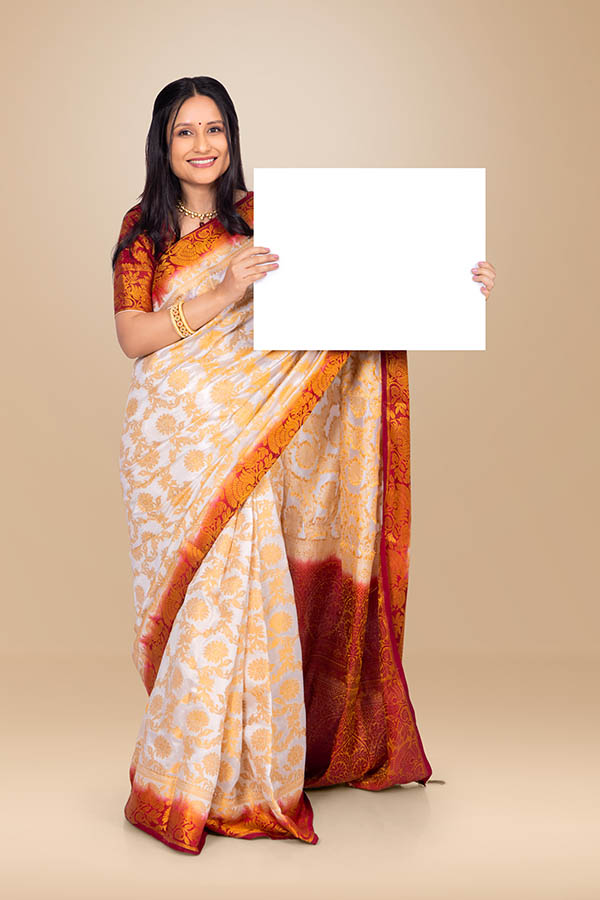 Smiling Indian woman holding blank placard in traditional festive saree