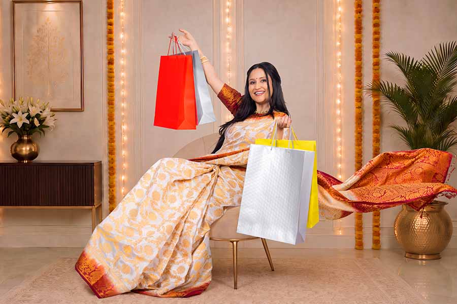 Indian woman holding shopping bags during Diwali celebration at home