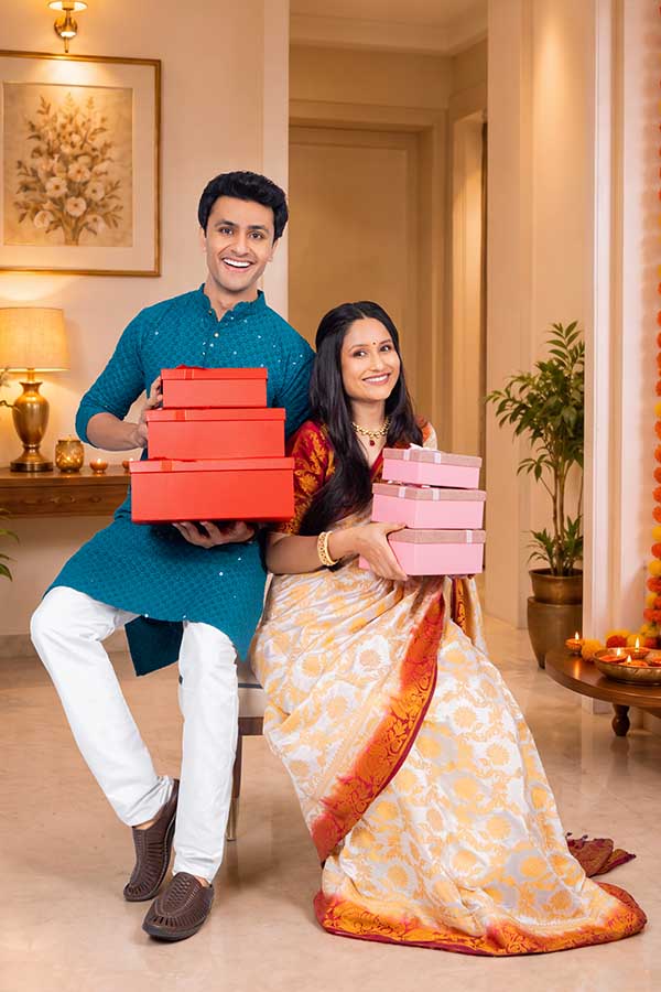 Indian couple smiling with gift boxes during Diwali celebration