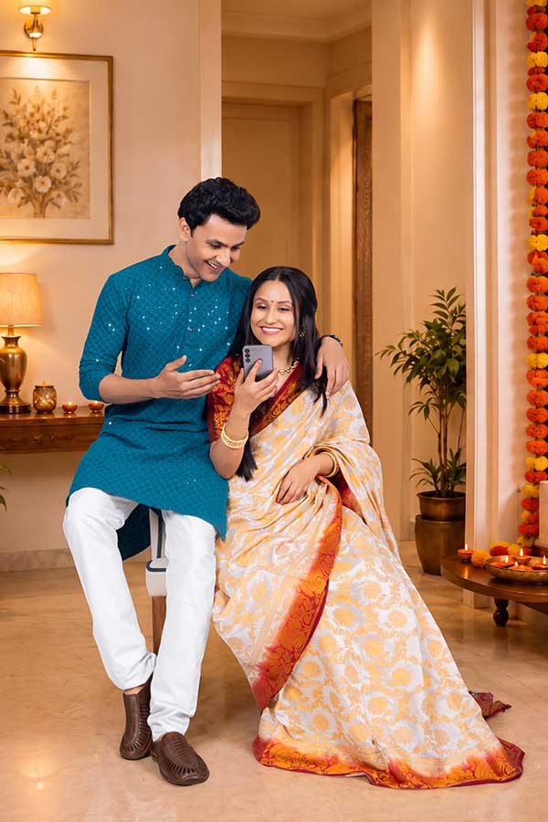 Indian couple using smartphone together during Diwali celebration at home