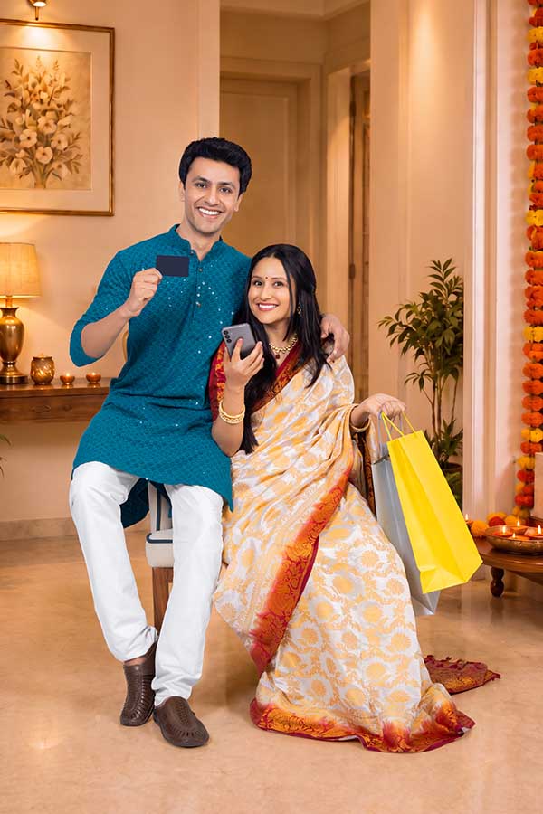 Indian couple celebrating Diwali with shopping bags smartphone and payment card