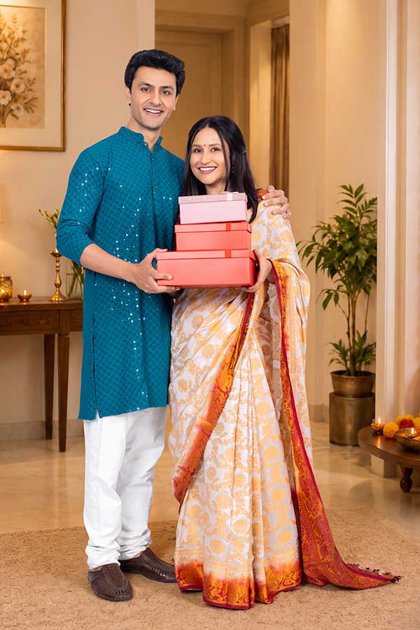 Indian couple holding gift boxes together during Diwali celebration at home