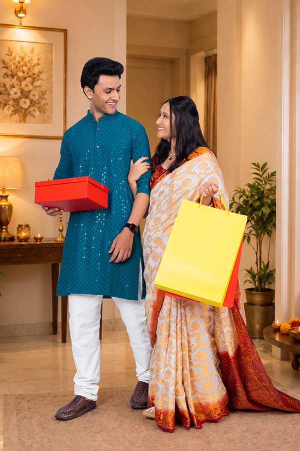 Indian couple carrying gift box and shopping bags while celebrating Diwali at home