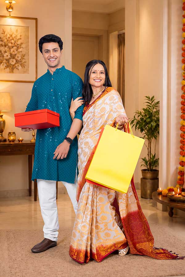Indian couple carrying gift box and shopping bag during Diwali celebration at home