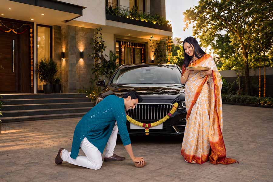 Young Indian couple performing traditional pooja for new car purchase
