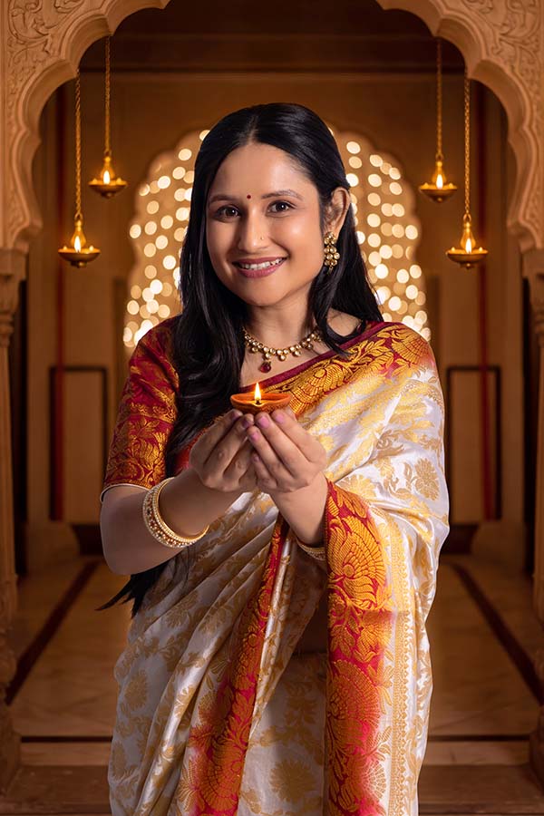 Indian woman offering glowing oil lamp during festive celebration indoors