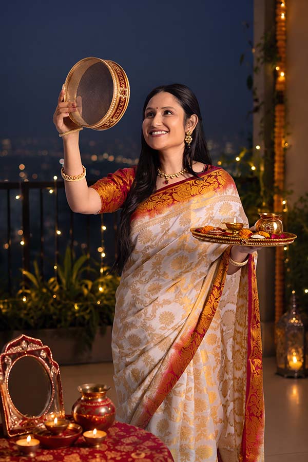 Indian woman performing Karwa Chauth moon ritual on decorated balcony