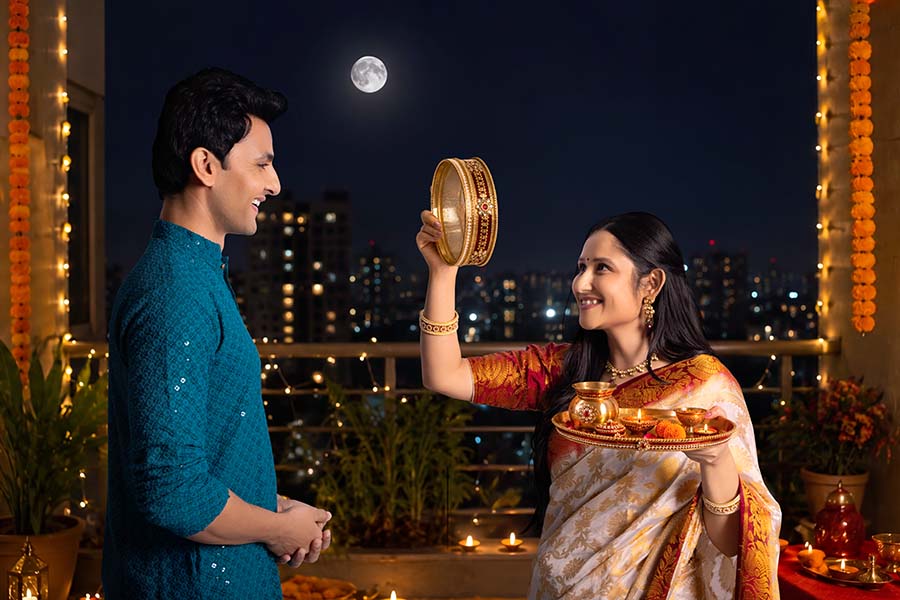 Indian wife performing Karwa Chauth ritual with husband under full moon