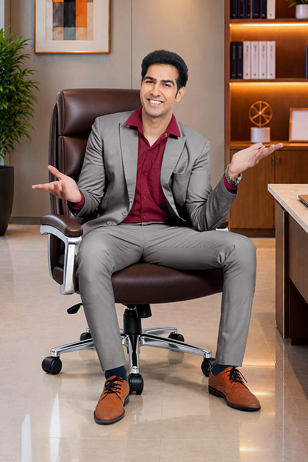 Indian businessman sitting in office chair with open hand gestures