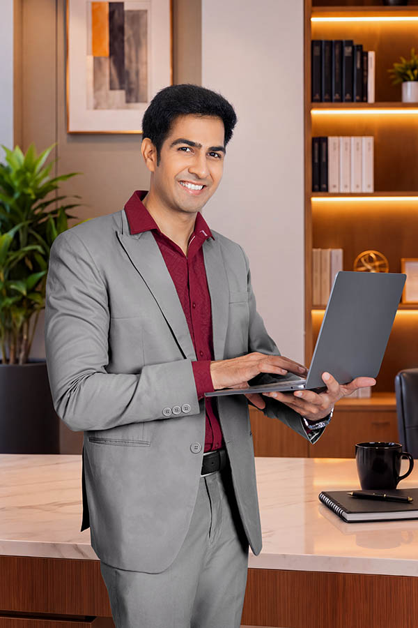 Smiling male executive holding laptop in modern corporate office