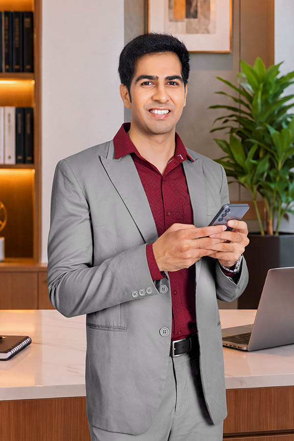 Smiling male professional using smartphone in modern office